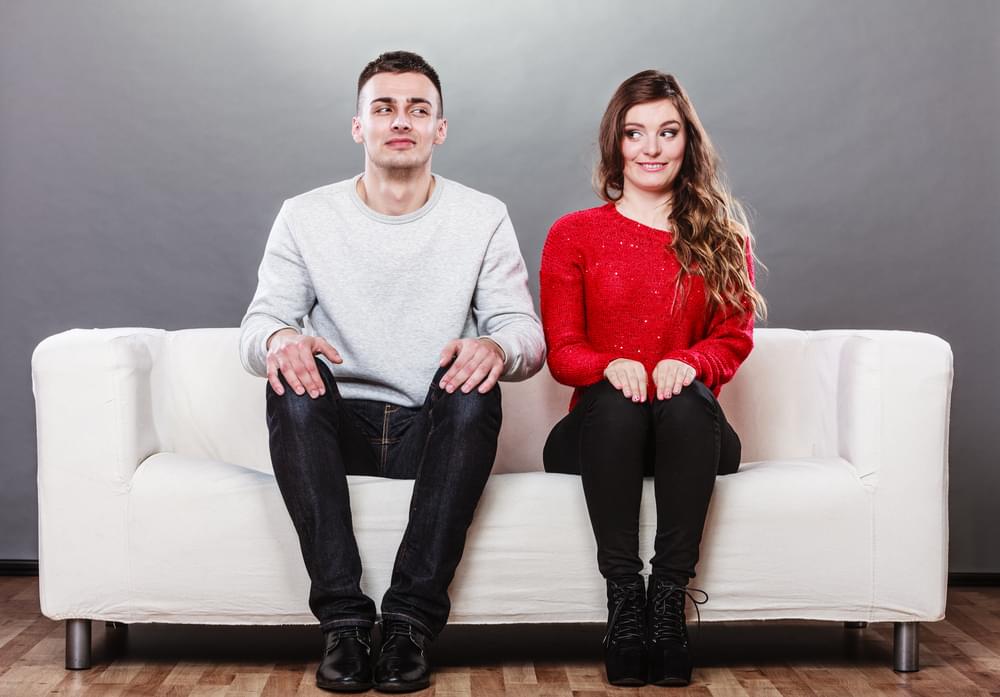 Two people awkwardly sitting on a couch